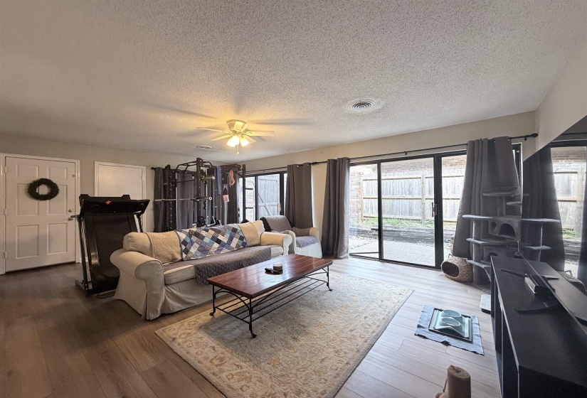 Spacious interior featuring wide plank wood-finish flooring, a ceiling fan, and sliding glass doors leading to an outdoor space