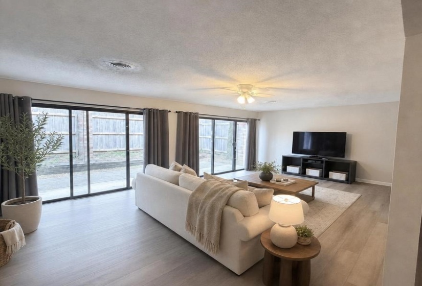 Spacious living area featuring light wood-finish flooring and multiple sliding glass doors for abundant natural light