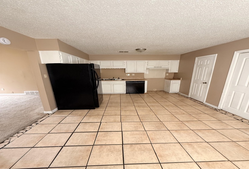 Kitchen featuring neutral-toned tile flooring, white cabinetry, and black appliances