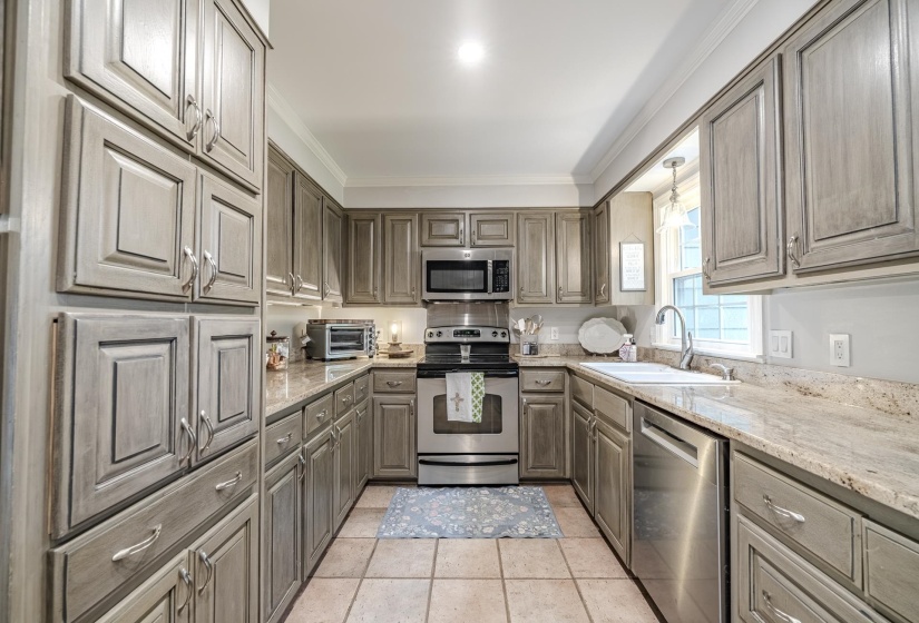 Kitchen featuring extensive cabinetry with paneled doors, light-toned countertops, and tile flooring