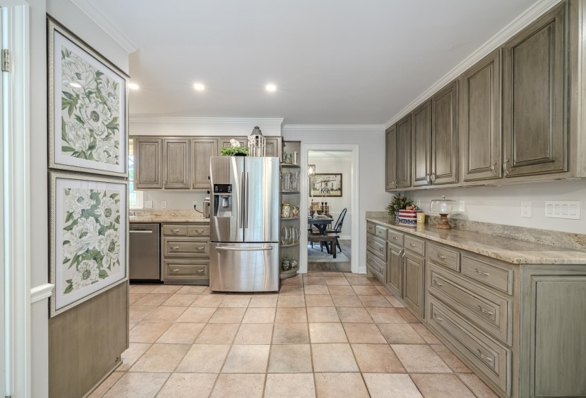 Expansive kitchen featuring stone tile flooring, extensive cabinetry with a washed finish, stainless steel appliances, and light-toned countertops