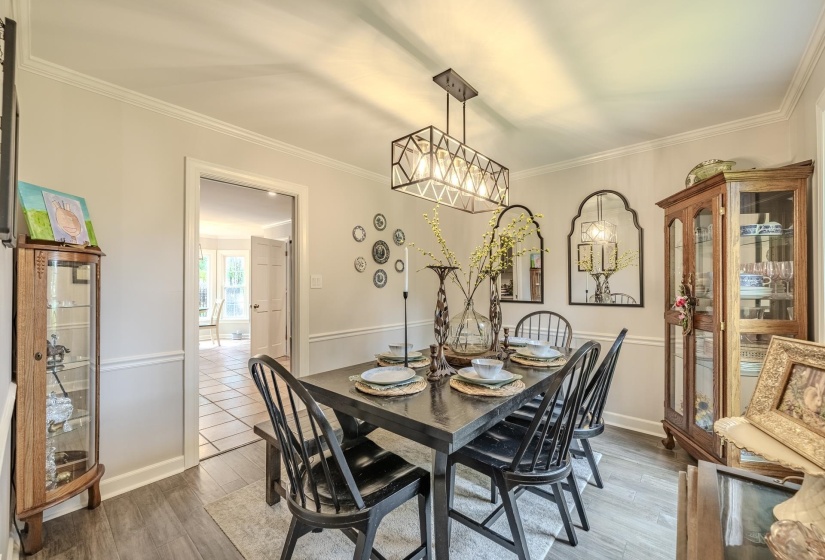 Dining area featuring wood-finish flooring, crown molding, and wainscoting
