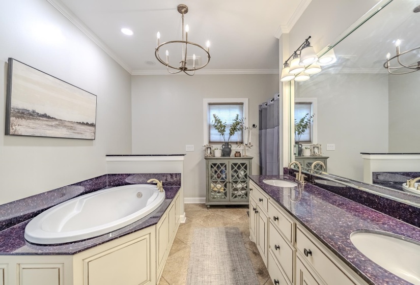 Bathroom featuring a built-in soaking tub with unique purple-flecked countertops and a dual vanity with undermount sinks