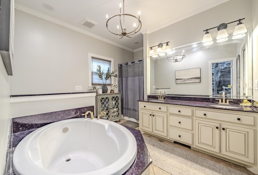 Spacious bathroom featuring a built-in soaking tub, dual vanity with undermount sinks, large mirror, and crown molding