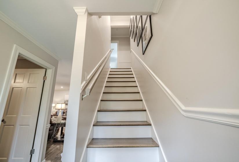 Staircase featuring wood-finish treads, white risers, and a white handrail