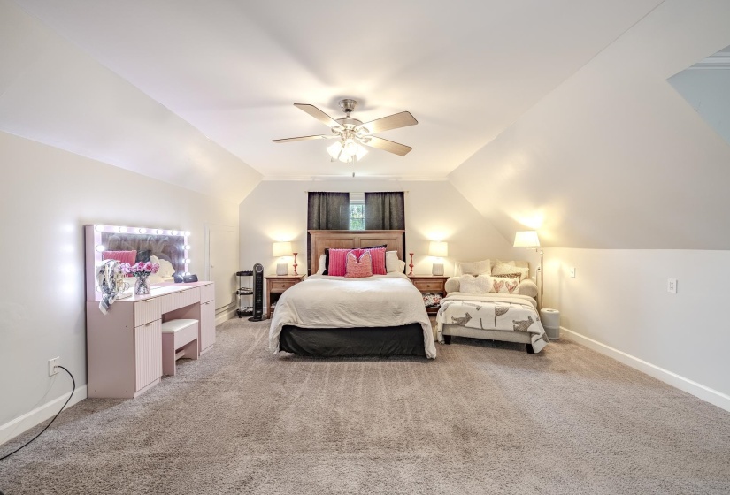 Spacious room featuring vaulted ceilings, neutral-toned carpet, a ceiling fan with integrated lighting, and multiple wall outlets
