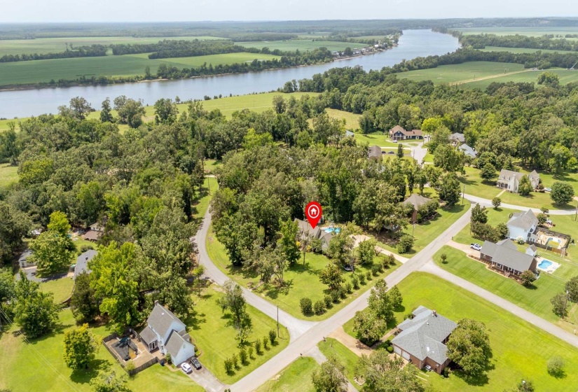 Expansive rural property featuring a large body of water, mature trees, and a residential community