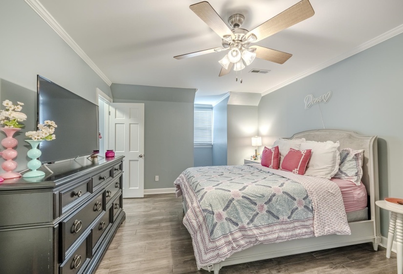 Spacious room with wood-finish flooring, light blue walls, and white crown molding