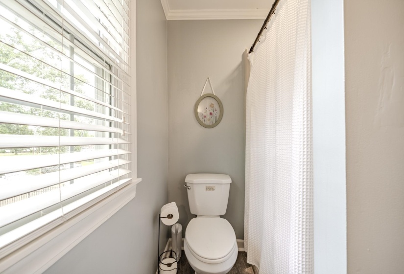 Bathroom featuring crown molding, neutral wall color, and a window with horizontal blinds