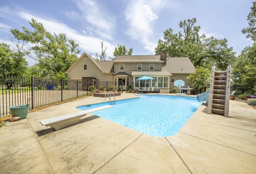 Expansive backyard featuring a large in-ground swimming pool with a diving board and slide