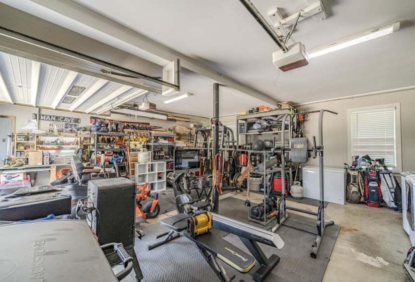 Spacious garage interior featuring concrete flooring, overhead fluorescent lighting, and a paneled wall with a single window