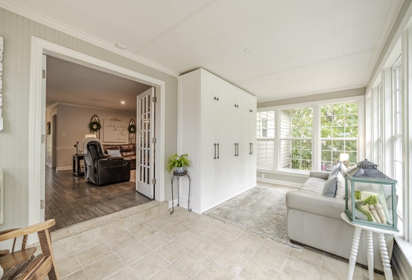 Sun-drenched room featuring tile flooring, extensive built-in cabinetry, and large windows