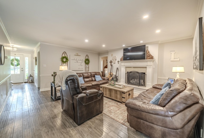 Spacious living area featuring wood-finish flooring, recessed lighting, and a white mantel fireplace