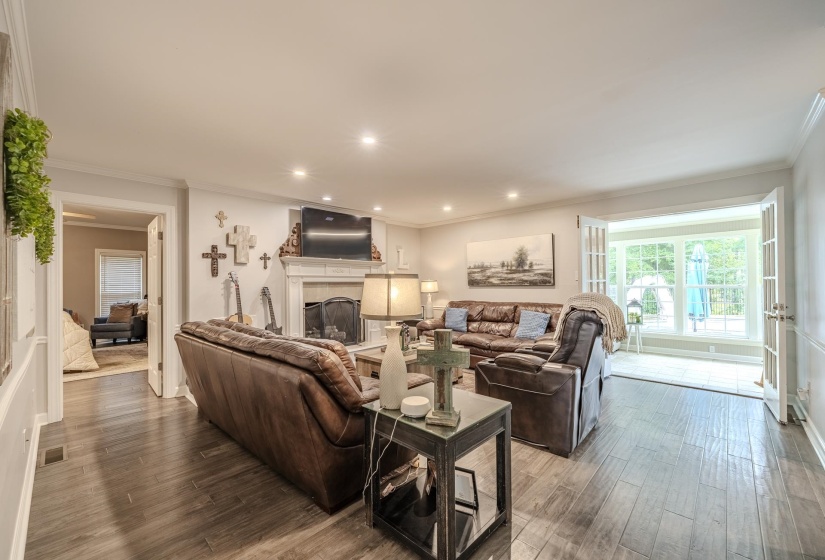 Spacious living area featuring wood-finish flooring, a white mantel fireplace, recessed lighting, and french doors opening to the exterior