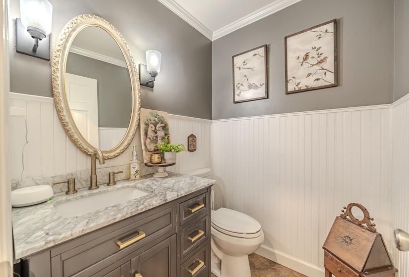 Vanity with a stone countertop, an undermount sink, and brushed gold hardware