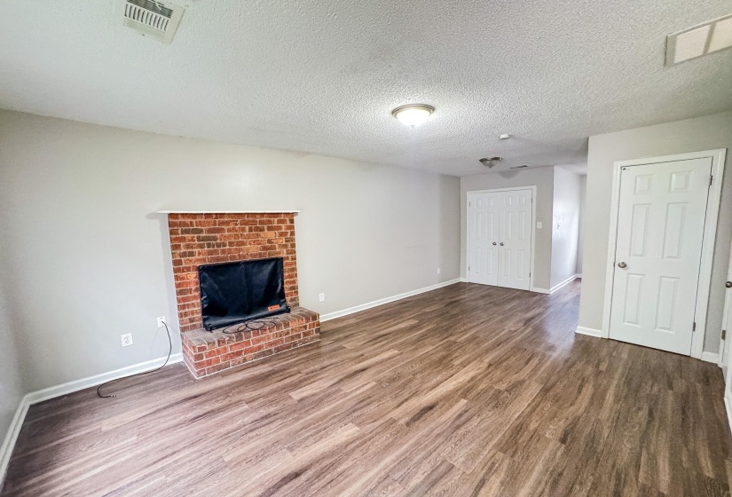 Living area featuring a brick fireplace with a white mantel, wood-finish flooring, and light gray wall paint
