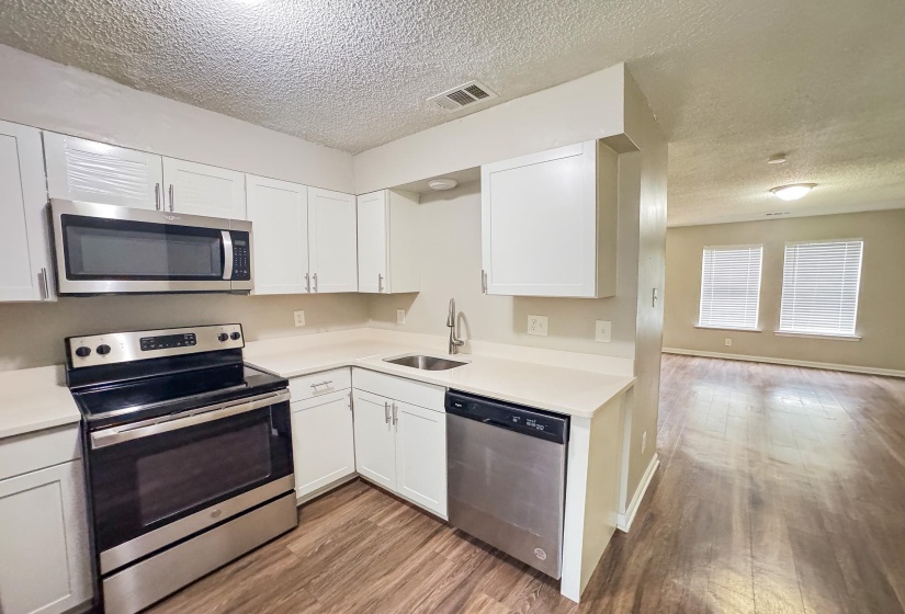 U-shaped kitchen featuring white cabinetry, stainless steel appliances, and a stainless steel sink with a gooseneck faucet