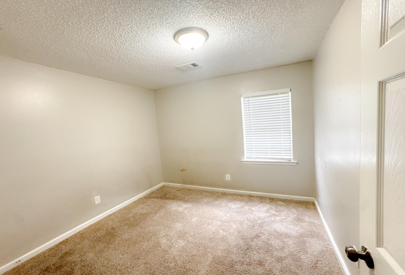 Carpeted room with neutral wall tones and a single window featuring blinds