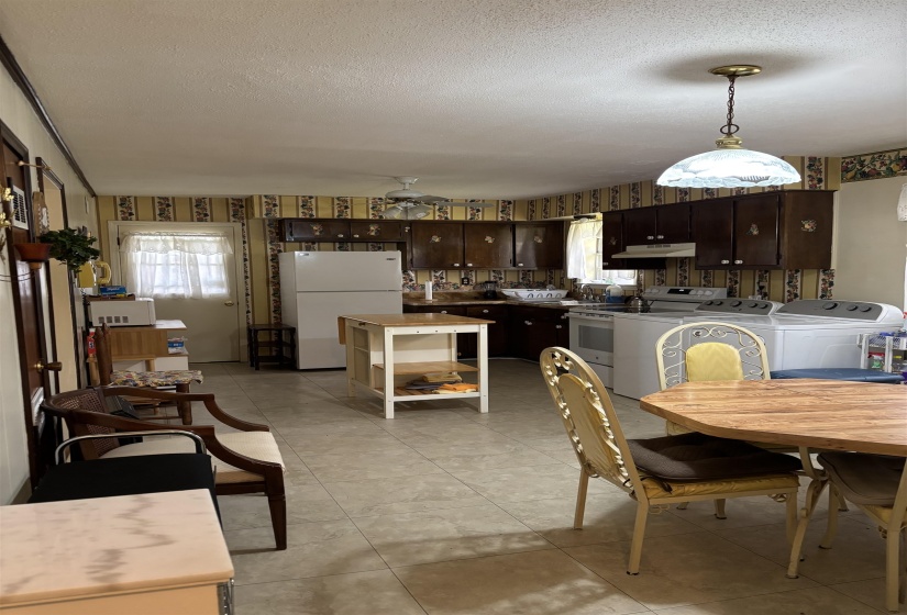 Dining space with a textured ceiling, ceiling fan, plenty of natural light, wallpapered walls, and washer and clothes dryer