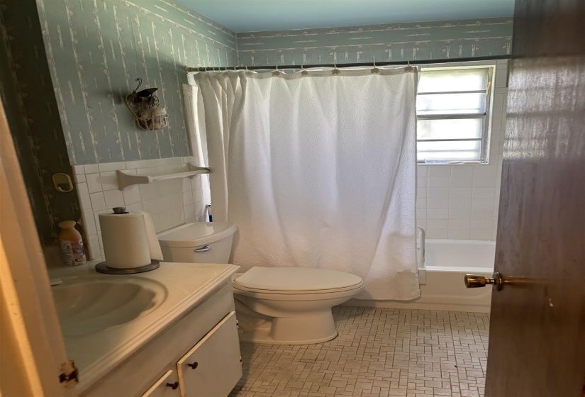 Full bath with vanity, shower / tub combo, wallpapered walls, and tile walls