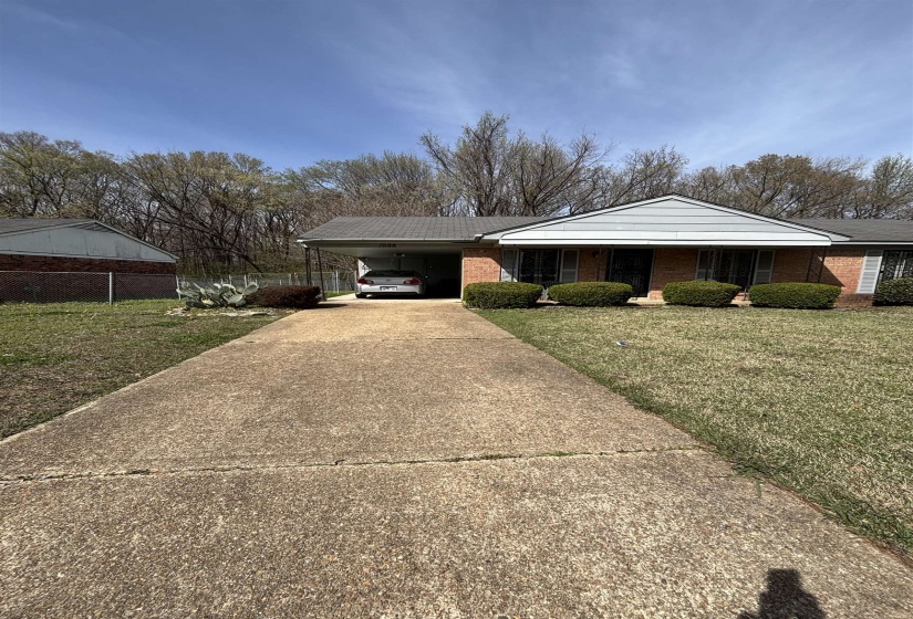 Single story home featuring a front lawn, concrete driveway, a carport, and brick siding