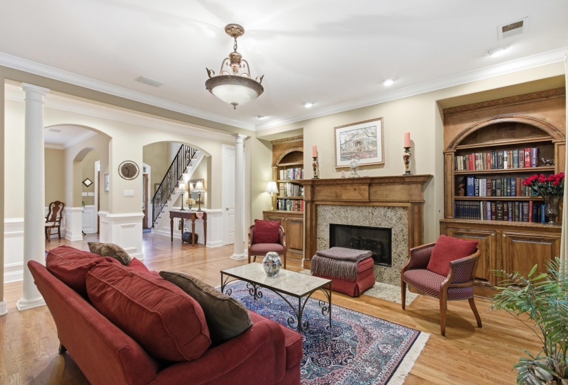 Living area featuring a fireplace with a stone surround and wood mantel, flanked by built-in wood cabinetry and arched bookshelves