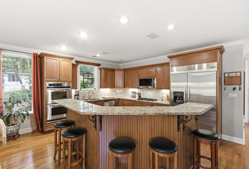 Kitchen featuring wood-finish cabinetry, granite countertops, and stainless steel appliances, including a double oven and refrigerator
