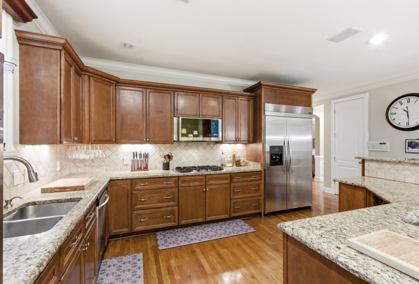 Kitchen featuring wood cabinetry, stainless steel appliances, a double basin sink, and granite countertops