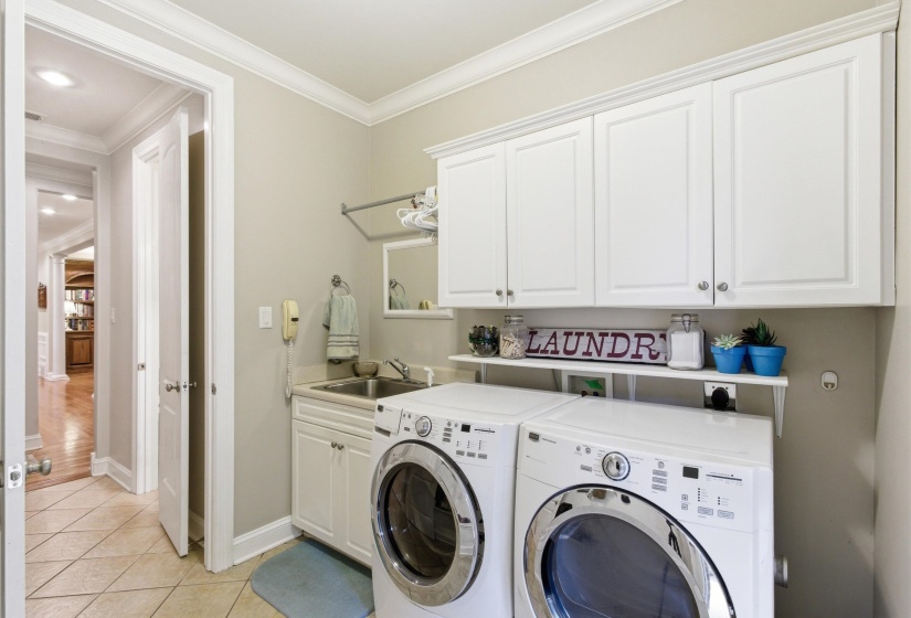 Laundry area featuring ceramic tile flooring, white shaker-style cabinetry, and a utility sink