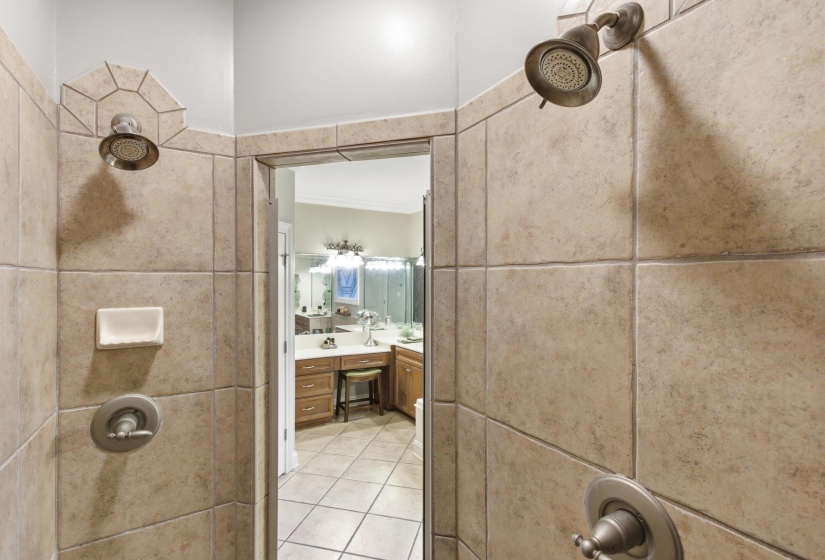 Tile-enclosed shower with dual showerheads and brushed nickel fixtures