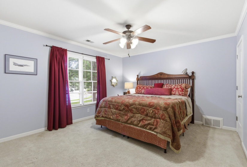 Carpeted bedroom featuring a ceiling fan with integrated lighting, crown molding, a large window with blinds, and white baseboards