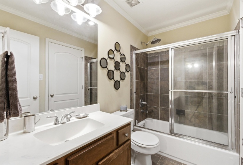 Bathroom featuring a single vanity with a white countertop, chrome faucet, and wood-finish cabinetry