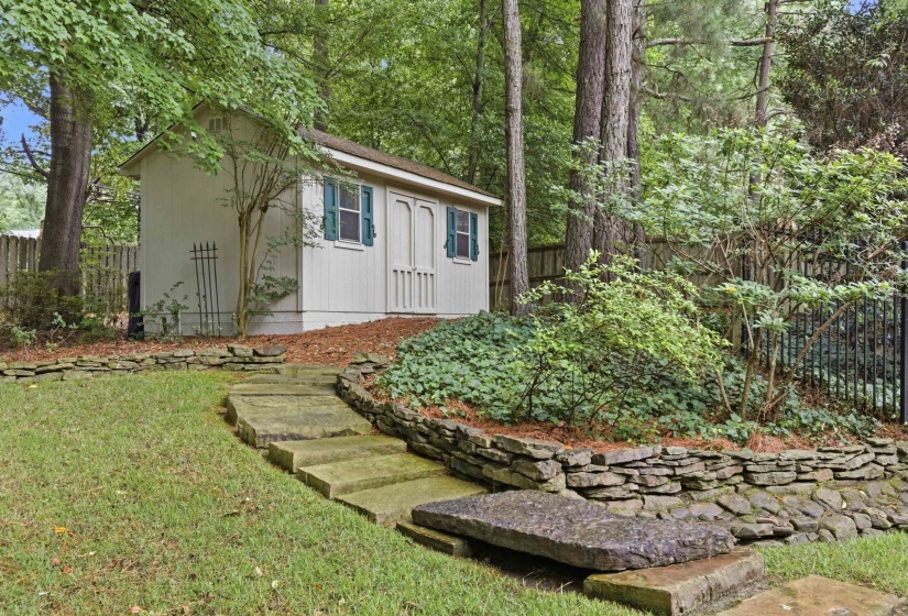 Freestanding storage shed with paneled double doors and louvered window shutters