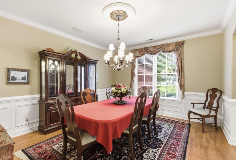 Dining area featuring wood-finish flooring, wainscoting, crown molding, and a decorative ceiling medallion