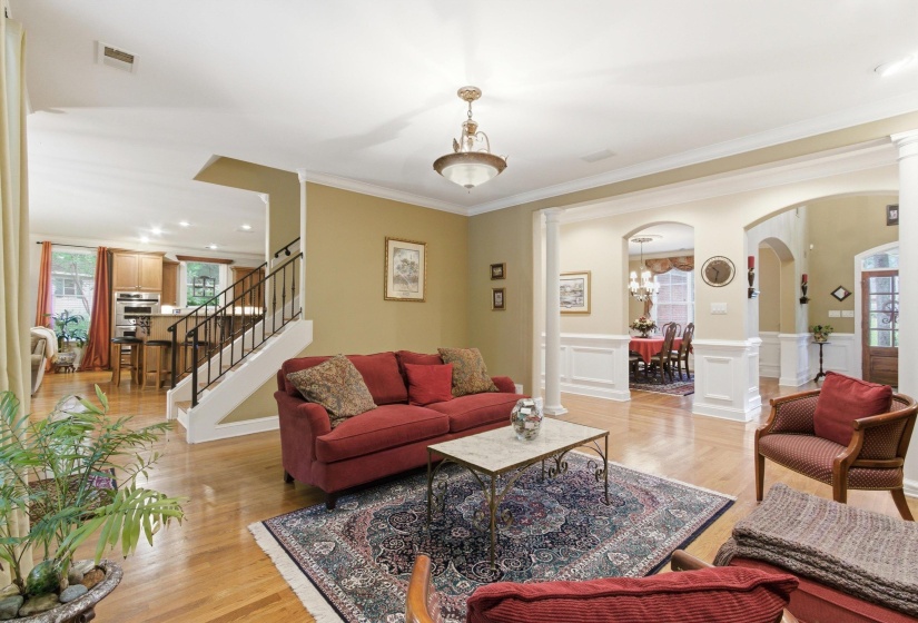 Expansive living area featuring hardwood flooring, crown molding, and a chandelier light fixture