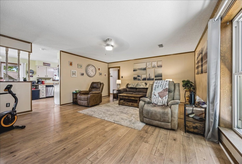 Wood-finish flooring extends throughout this expansive living area, featuring neutral wall tones and a ceiling fan