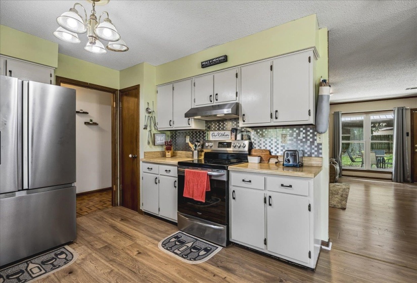 Kitchen featuring wood-finish flooring, white cabinetry with black hardware, and stainless steel appliances