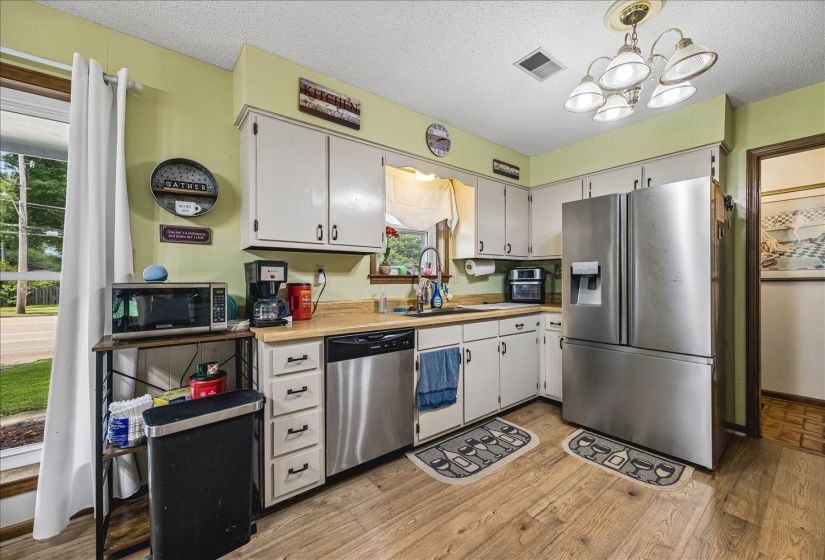 Kitchen featuring wood-finish flooring, white cabinetry, a stainless steel refrigerator, a stainless steel dishwasher, and a double-basin sink