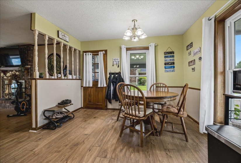 Open concept dining area featuring wood-finish flooring, a decorative chandelier, and natural light from multiple windows