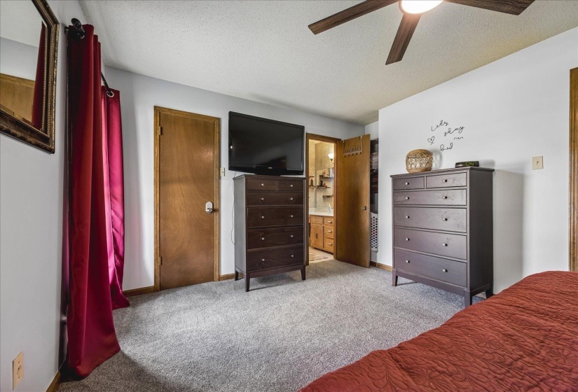 Carpeted room with a ceiling fan, light-colored walls, and a wooden door