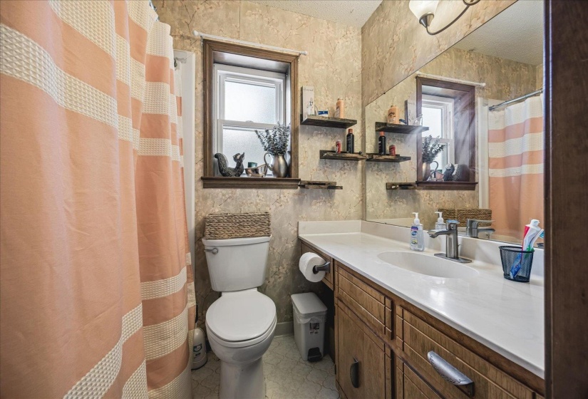 Bathroom featuring a wood-finish vanity with a white countertop and integrated sink