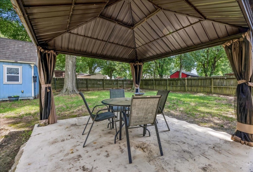 Outdoor metal gazebo with a solid roof, privacy curtains, and concrete patio