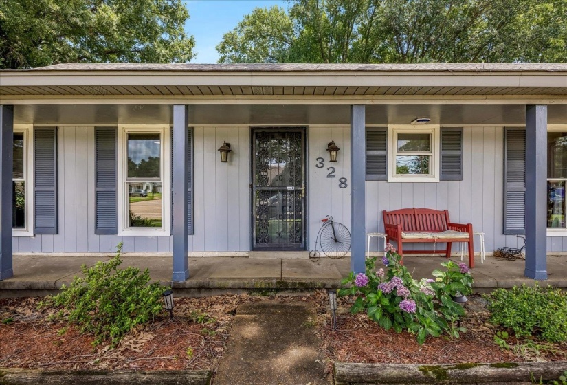 Exterior entry featuring a covered porch with blue support columns, light blue siding, and contrasting blue window shutters