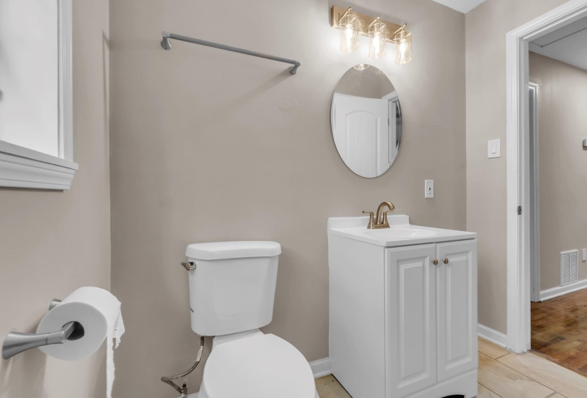 Bathroom featuring a white vanity with double doors, oval mirror, and a four-light fixture