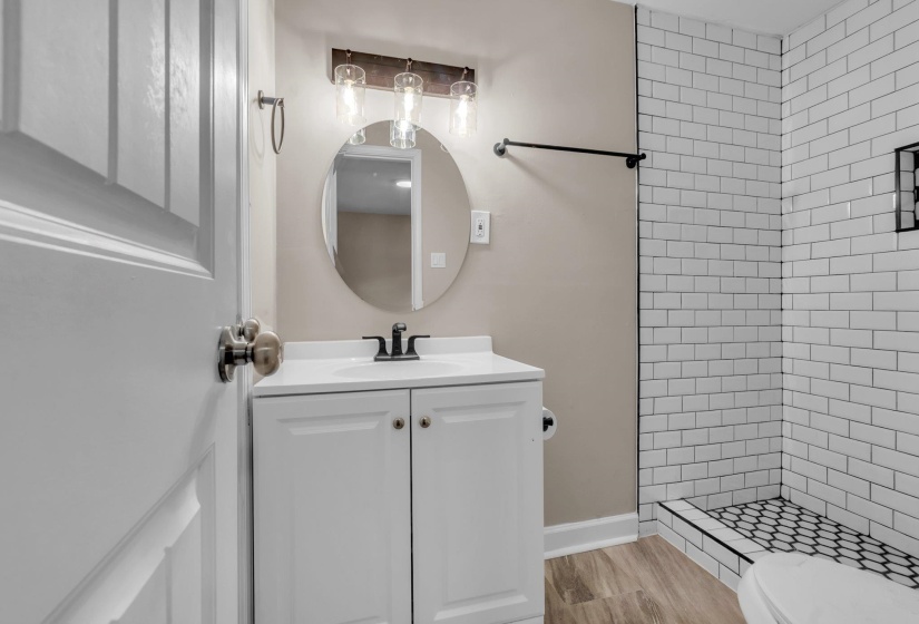 Bathroom featuring a white vanity with integrated sink, black faucet, and circular mirror