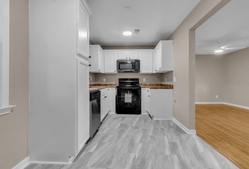 Kitchen featuring white shaker-style cabinetry, dark countertops, and stainless steel appliances