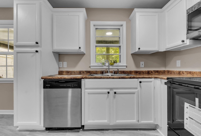 Kitchen with white shaker-style cabinetry, a stainless steel dishwasher, a stainless steel sink with a chrome faucet, and wood-finish countertops