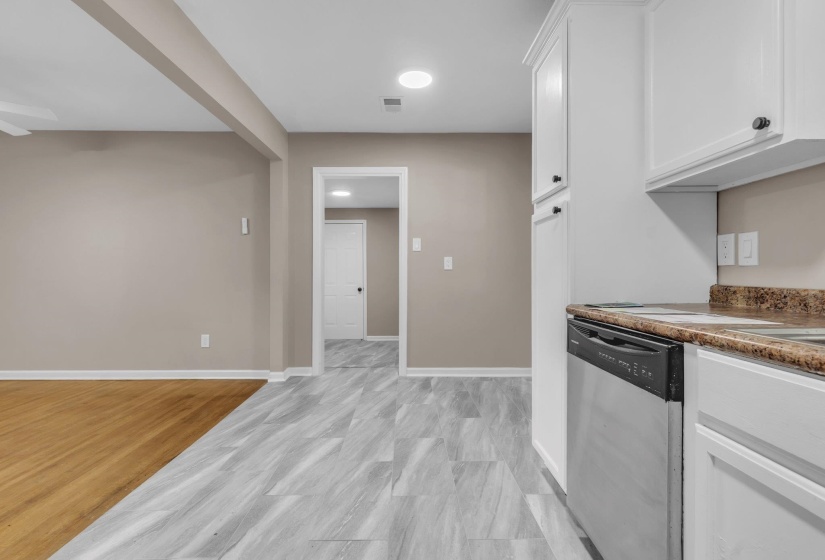 Kitchen area featuring white cabinetry, a built-in stainless steel dishwasher, and a stone-look countertop