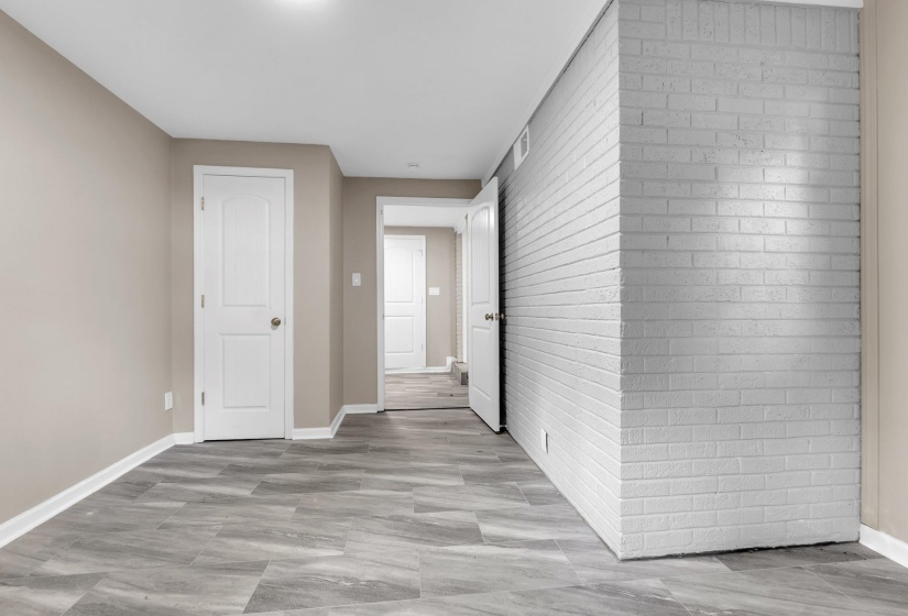 Spacious room featuring light gray brickwork, neutral wall paint, and gray wood-finish flooring