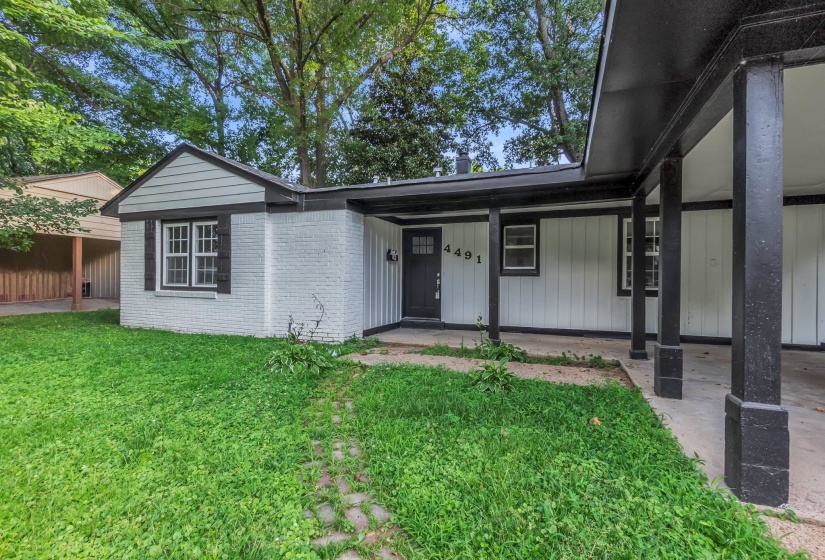 White brick and siding exterior with black trim, featuring a covered entryway with structural columns